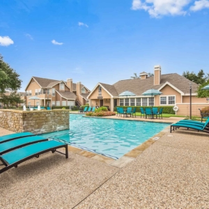 Large pool at Highlands of Valley Ranch surrounded by brightly colored patio furniture, bright potted plants and multiple seating areas